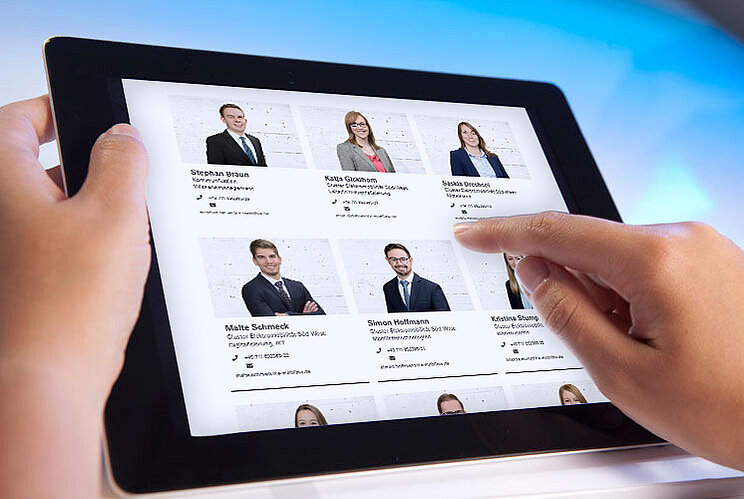 Zwei Hände halten ein Tablet mit Ansprechpartnern auf Internetseite