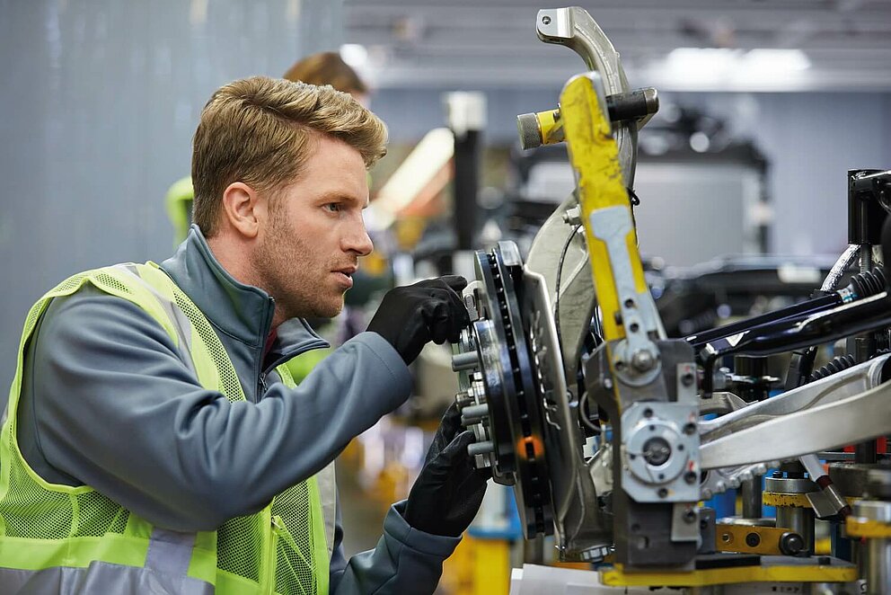 Junger Autobauer bei der Montage am Fließband