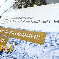 Detailsaufnahme des Plakates vor dem Neckar Forum Esslingen. Darauf steht Willkommen und Welcome auf dem Zulieferertag Automobilwirtschaft BW 2022!