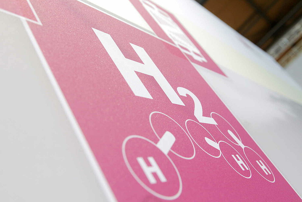 Piktogramm "H2" für Wasserstoff auf rotem Grund an einer Messewand