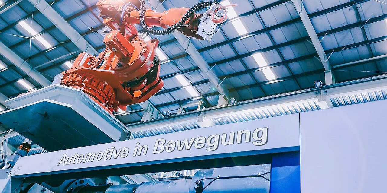 Roboterarm in der Produktion. Schriftzug "Automotive in Bewegung".